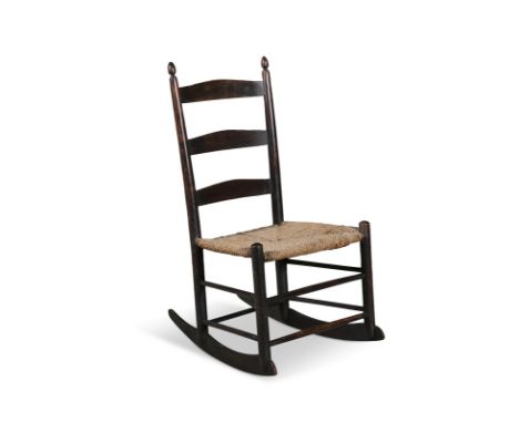 A SMALL BEECHWOOD 'SHAKER' ROCKING CHAIR, with three-bar ladder back and woven rush seat, 72cm high x 39cm wideProvenance: Mc