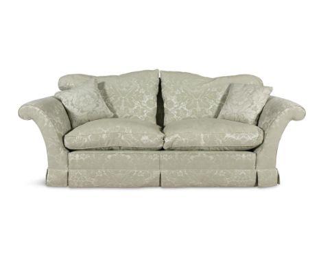 AN UPHOLSTERED HUMP-BACK SOFA, covered in pale green floral damask, with twin scroll ends, loose seat cushions and castors, 2