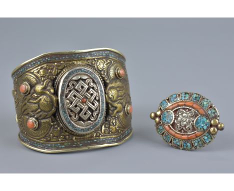A large Tibetan metal bangle with coral coloured stones decorated with two dragons and incised decoration to interior togethe