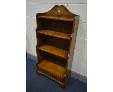 A REPRODUCTION OAK WATERFALL OPEN BOOKCASE, with a raised top, four shelves above a single long drawer, on bracket feet, widt