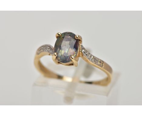 A 9CT GOLD TOPAZ AND DIAMOND DRESS RING, designed with a four claw set, oval cut topaz (mystic coated), to the cross over sty