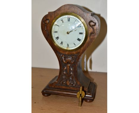 AN OAK ARTS AND CRAFTS CARVED BALLOON CASED MANTEL CLOCK, white enamel dial (s.d.), with Roman and Arabic numerals, pull off 