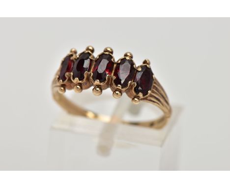 A 9CT GOLD FIVE STONE GARNET RING, designed with five oval cut garnets, applied bead work to the surrounds, textured shoulder