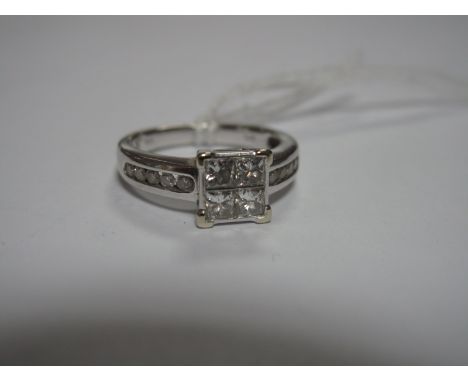 A Modern Princess Cut Diamond Set Ring, collet rubover set to the centre with four uniform stones, between channel set brilli