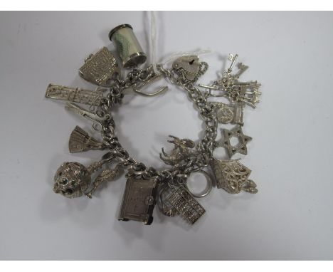 A Curb Link Charm Bracelet, suspending numerous novelty charm pendants, including fan, banknote in cylindrical case, Holy Bib