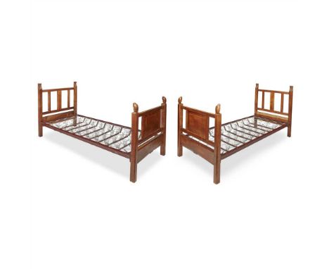 COTSWOLD SCHOOL PAIR OF ARTS &amp; CRAFTS CARVED WALNUT SINGLE BEDS, CIRCA 1930 the headboards with leaf-carved finials, the 