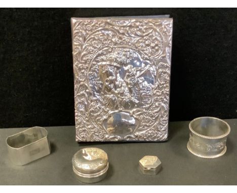 A silver fronted address book, embossed with a Minstrel Lute player and figures, London 1990;  silver napkin rings;  pill box