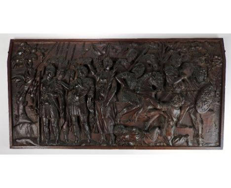 An 18th century continental carved oak panel depicting a triumphant battle scene, the tapering panel in a later oak surround,