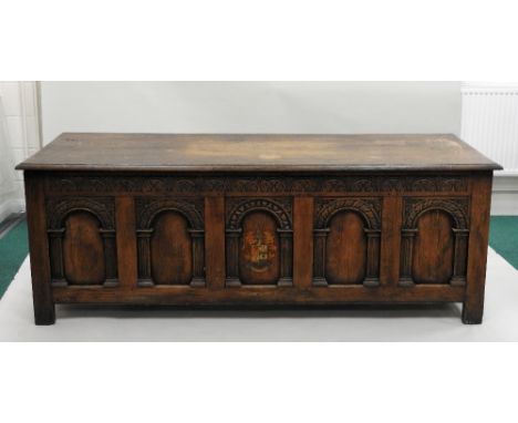 A joined oak coffer of country house proportions, the rectangular boarded lid over a five panel front in the nonsuch manner, 