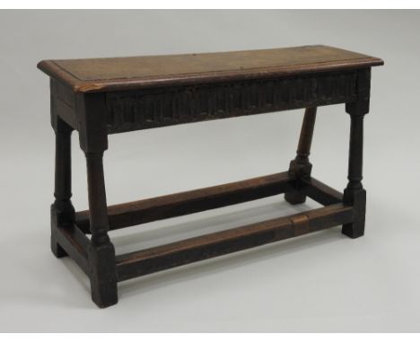 A 17th century style joined oak bench, the rectangular seat with moulded edge over a thumb moulded front facing frieze, on tu