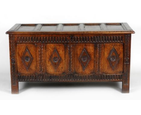 An early 18th century joined oak coffer, the five panel hinged lid over a thumb moulded frieze and four lozenge carved panels
