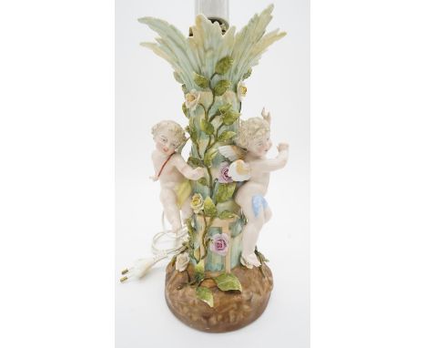 A 20th century Sitzendorf hand painted porcelain table lamp with three cherub figures and the stem as a palm tree wrapped wit