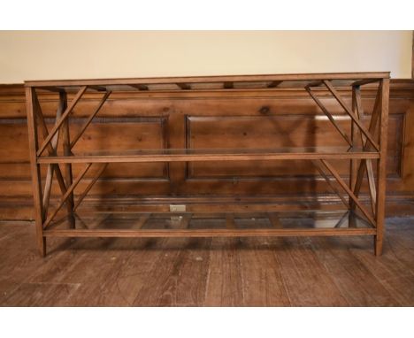 An X framed teak console table with three plate glass tiers. H.72 W.140 D.33cm 