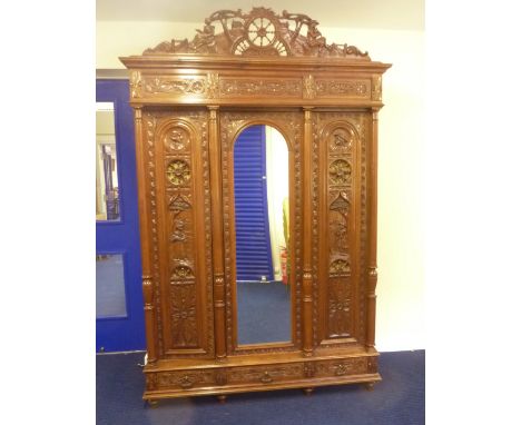 Impressive French oak triple wardrobe, all over carved detail, depicting period figures, rosettes within Celtic scrolls, open