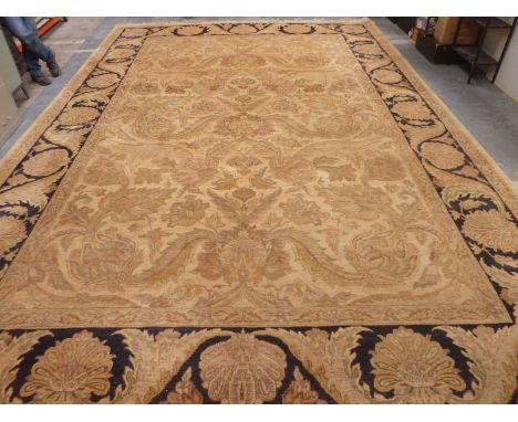 Large Eastern style wool on cotton carpet, the pale gold field with scrolling floral and foliate motifs surrounded by a black