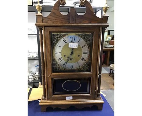 A late 20thc oak cased mantle clock, the swan neck pediment with brass finials above a glazed panel enclosing a brass face wi