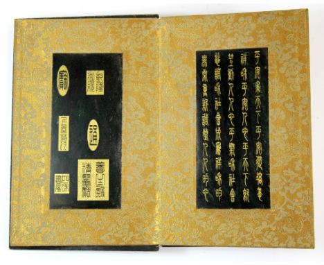 A lovely Chinese book with wooden covers and silk mounted pages of engraved dark green jade panels with gilded engraving, 15 