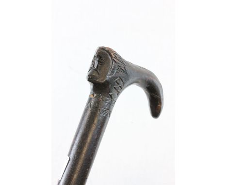 An ebonised sword stick with handle in the form of a face 