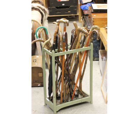 A painted oak stick stand with original metal drip tray and an assortment of 19 vintage walking sticks (including brass and h