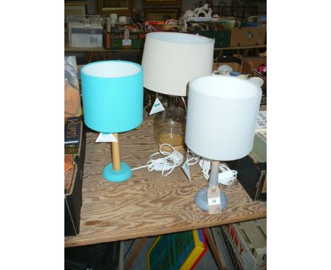 Three modern table lamps, a glass bottle shaped lamp and two with wooden columns c/w shades.

*Please note that this lot is s