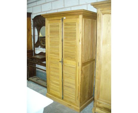 A Light oak French style wardrobe with two louvre doors raised on a plinth base.