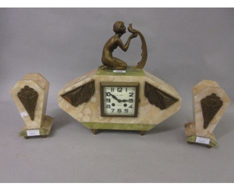 Art Deco beige and green onyx mantel clock with gilt metal mounts, surmounted by a kneeling figure of a girl with an exotic b