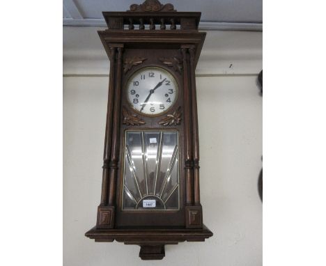 Early 20th Century Continental beechwood Vienna type wall clock with a spindle gallery above a beveled glass door, flanked by
