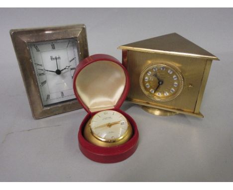 Looping gilt metal eight day travel clock in a leather case, together with a French revolving desk clock / thermometer / baro