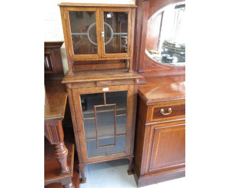 Oak Arts and Crafts style narrow bookcase with two leaded glazed doors above a single astragal glazed door raised on square s