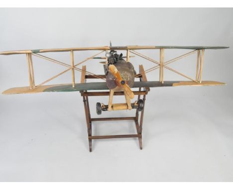 A wooden scale model of a British WWI bi-plane, with pilot and machine gun, camouflage markings, with undercarriage, on a woo