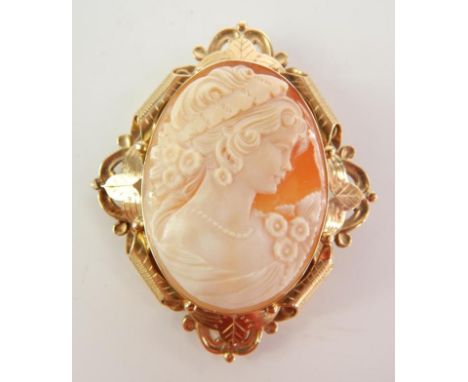 A cameo brooch, bust portrait of a lady, set within a floral scrolled yellow metal frame, unmarked, 6cm high. 