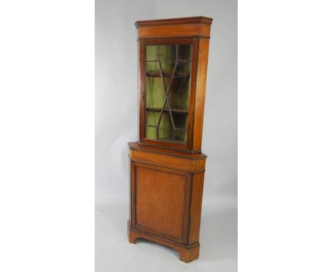 An Edwardian mahogany and satinwood cross banded corner cabinet, the pediment over an astragal glazed door enclosing two shel