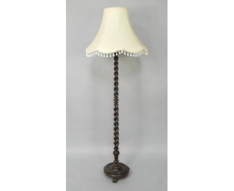 An oak spiral twist standard lamp, raised on a circular base and three scroll feet, with shade, 180cm high.