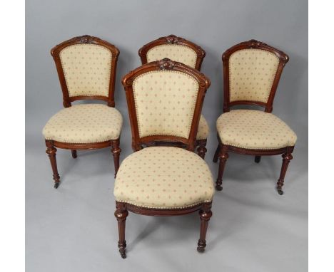 A set of four Victorian mahogany spoon back single dining chairs, with over stuffed seats and backs, raised on turned and flu