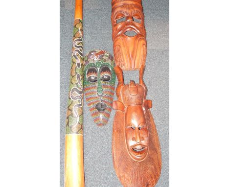 A didgeridoo and three carved wooden tribal masks.