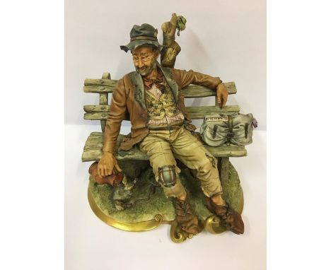 A Capo Di Monte Figure, Modelled as a drunk sitting on a garden bench, having gilded decoration the base, made in Italy and b