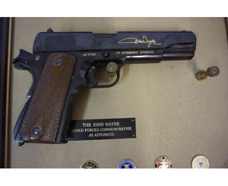 The John Wayne Armed Forces Commemorative Replica 45 Automatic Pistol by Franklin Mint, in a frame with four U.S military ena