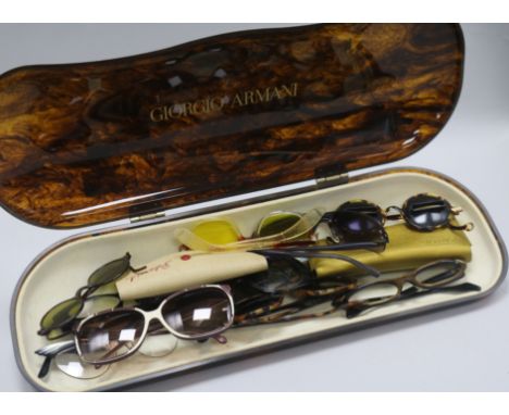 A collection of twelve vintage and designer glasses in an Armani shop display case