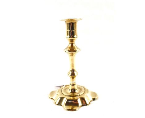 An 18th Century seamed Brass candlestick with knopped stem and wide petal shaped base, 8" high