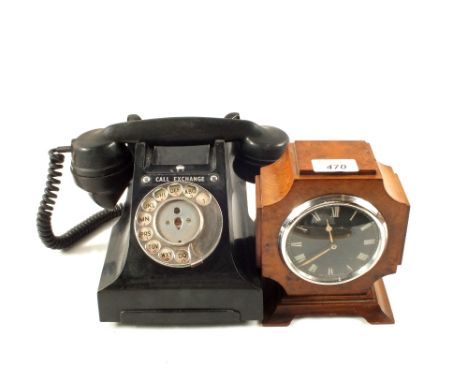 A black Bakelite telephone and a Walnut mantel clock