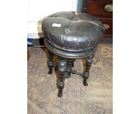 A circular leatherette/rexene upholstered circular Piano Stool standing on a base with four turned legs and a central pillar 