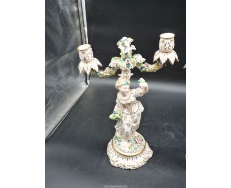 An impressive pair of flower encrusted Continental porcelain candelabra, one elegantly depicting a young lady leaning against