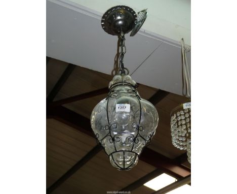 A clear blown glass celing light with wire surround.