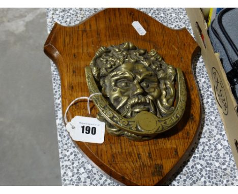A Cast Brass Door Knocker In The Form Of A Green Man Mask And Set On An Oak Shield