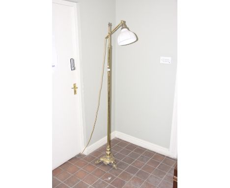 An early 20th Century brass standard lamp 
Rising from a tri-form base and paw feet extending to a slender stem with adjustab