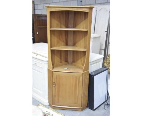An Ercol light elm free standing corner display cabinet
Having two enclosed shelves above a single panelled cupboard door app