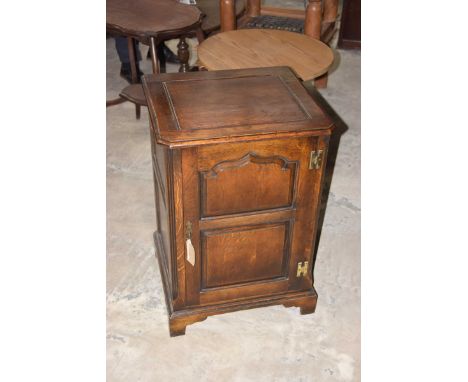 A good quality reproduction oak side cabinetThe square top with front canted corners above a fielded panel door flanked by ca