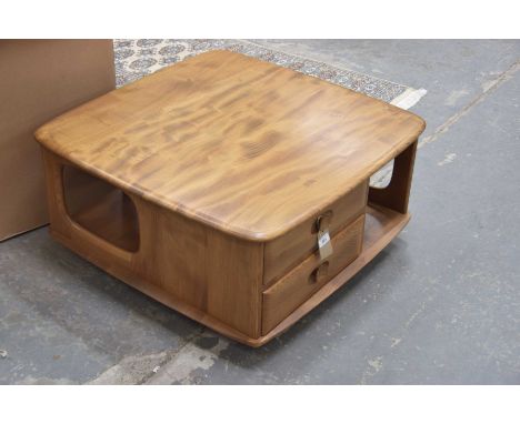 An Ercol light elm coffee table
The square top with rounded corners above two frieze drawers and shaped recesses raised on ca