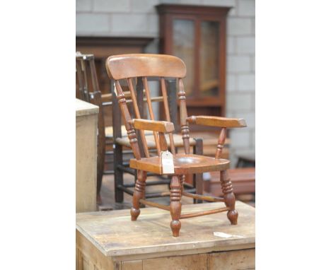 A late 19th Century oak and beech wood child's Windsor style commode chairHaving a stick back above out swept arms, the seat 