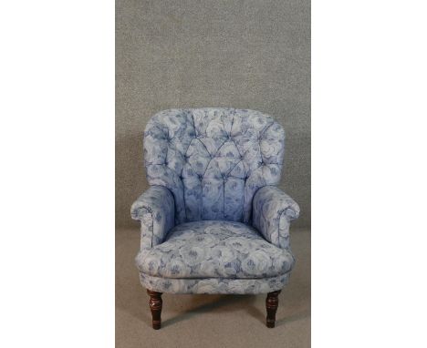A Victorian style armchair, with button back, upholstered in blue fabric with flowerheads, on turned mahogany legs. 